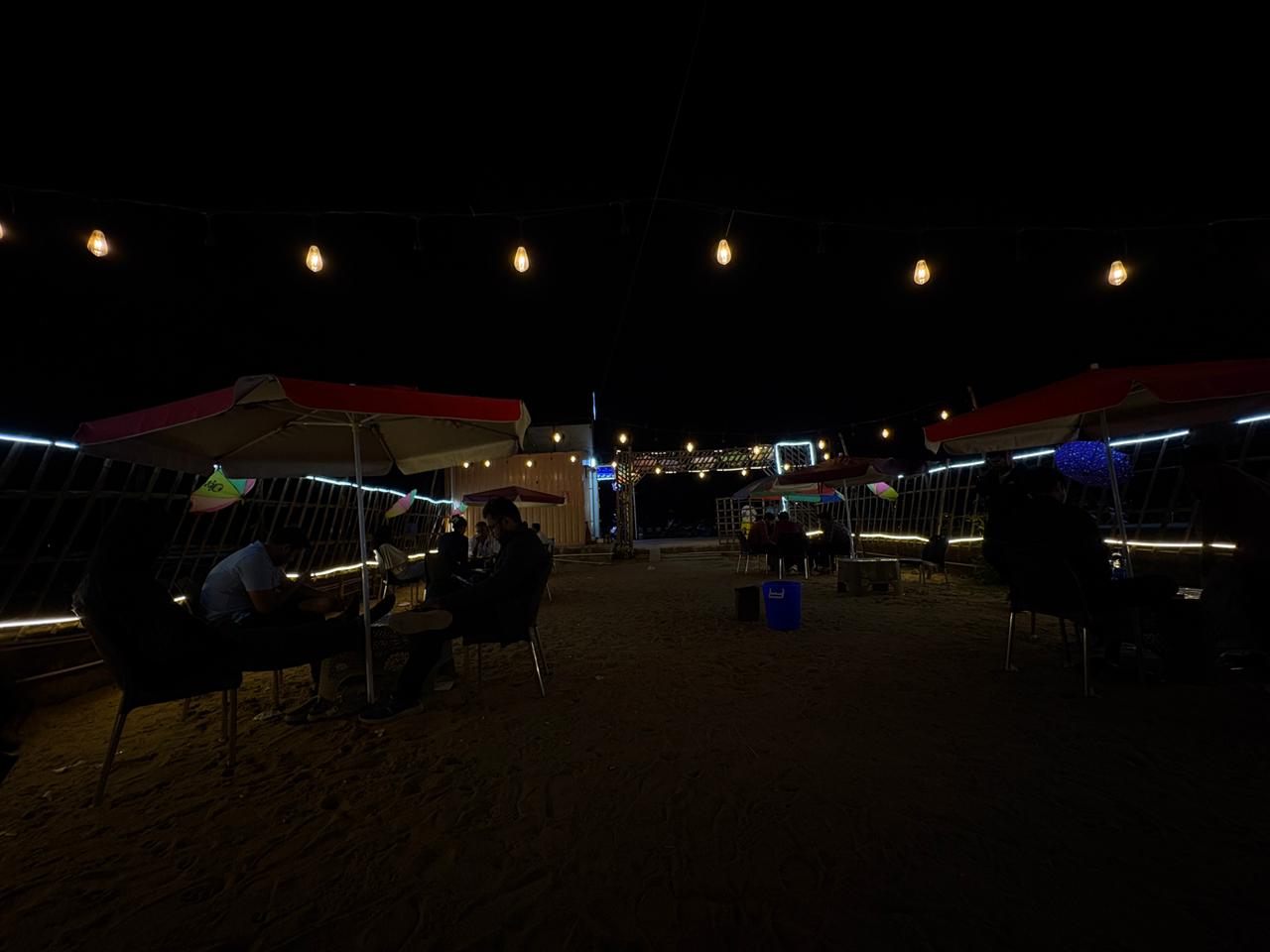 Open seating area with string lights and umbrellas